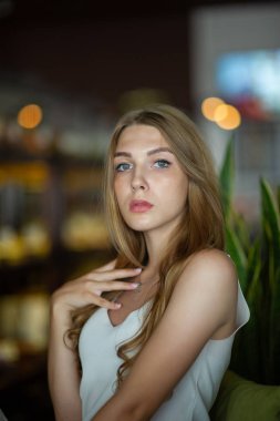 Mavi gözlü bir kız şehir kafede oturuyor. kahverengi dalgalı saç modeli ile kadın. Yaşam tarzı kavramı.