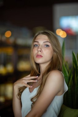 Mavi gözlü bir kız şehir kafede oturuyor. kahverengi dalgalı saç modeli ile kadın. Yaşam tarzı kavramı.