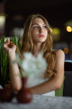 Mavi gözlü bir kız şehir kafede oturuyor. kahverengi dalgalı saç modeli ile kadın. Yaşam tarzı kavramı.