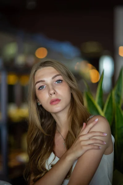 Дівчина з блакитними очима сидить у міському кафе. жінка з коричневою хвилястою зачіскою. Концепція стилю . — стокове фото