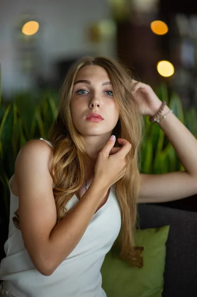 Mädchen mit blauen Augen, die auf einem städtischen Café sitzen. Frau mit brauner welliger Frisur. Lifestylekonzept. — Stockfoto