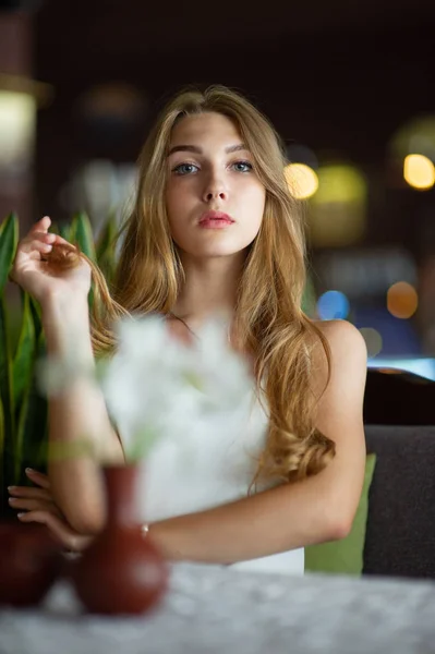 Chica con ojos azules sentada en la cafetería urbana. mujer con peinado ondulado marrón. Concepto de estilo de vida . — Foto de Stock
