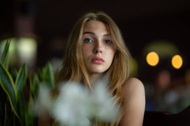 Mavi gözlü bir kız şehir kafede oturuyor. kahverengi dalgalı saç modeli ile kadın. Yaşam tarzı kavramı.