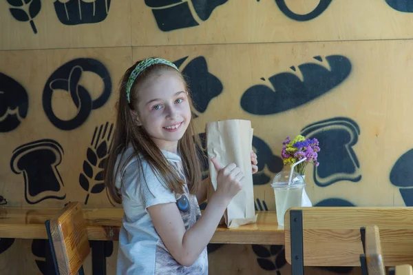 Mała dziewczynka trzyma papierową torbę z jedzeniem w rękach — Zdjęcie stockowe