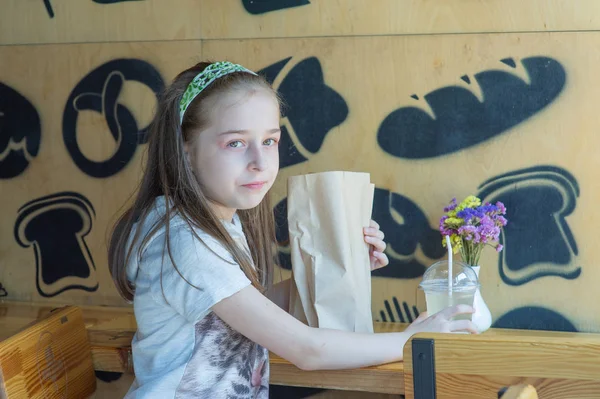 Niña sosteniendo una bolsa de papel con comida en las manos — Foto de Stock