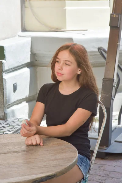 Little girl in a black t-shirt in a cafe — Stock Photo, Image