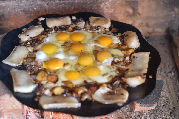 Eggs are fried on a fire in the street. Fried eggs with bacon.