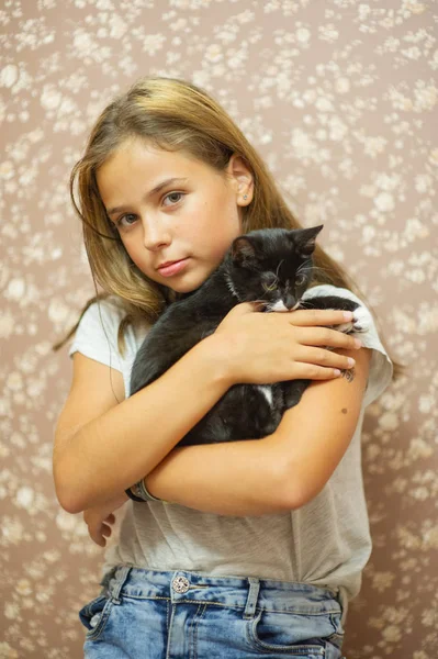 Meisje 10 jaar oud en een zwart-wit kitten. — Stockfoto