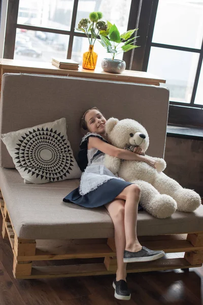 Pretty little girl is whispering to teddy bear and smiling