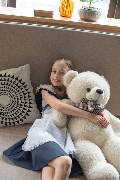 Pretty little girl is whispering to teddy bear and smiling