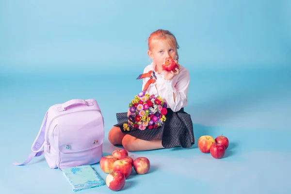 Portrait of beautiful young first-grader. First-grader girl in the studio with flowers