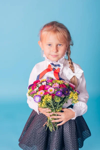 Portrait of beautiful young first-grader. First-grader girl in the studio with flowers