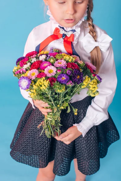 Портрет красивого молодого першокласника. Дівчина-першокласниця в студії з квітами — стокове фото