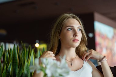 Mavi gözlü bir kız şehir kafede oturuyor. kahverengi dalgalı saç modeli ile kadın. Yaşam tarzı kavramı.