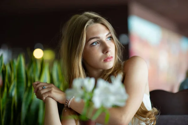 Fille aux yeux bleus assise sur un café urbain. femme avec une coiffure ondulée brune. Concept de style de vie . — Photo