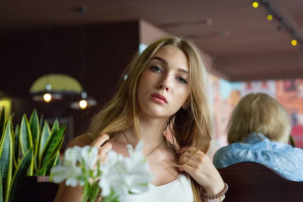 Chica con ojos azules sentada en la cafetería urbana. mujer con peinado ondulado marrón. Concepto de estilo de vida . — Foto de Stock