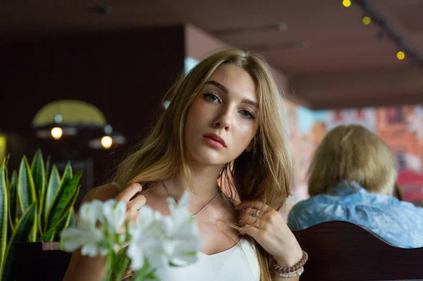 Chica con ojos azules sentada en la cafetería urbana. mujer con peinado ondulado marrón. Concepto de estilo de vida . — Foto de Stock