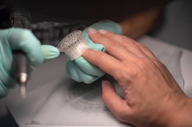 Bir çivi ile manikür el mavi hijyenik eldiven bir manikür el yatıyor.