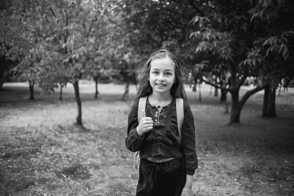 Schülerin geht in der Morgensonne zur Schule. 9-jährige Schülerin auf dem Schulhof. Schwarz-Weiß-Foto. — Stockfoto