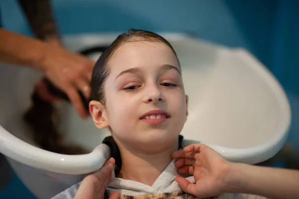 Peluquería estilista hace un peinado para una niña linda en un salón de belleza. Peluquería, corte de pelo . —  Fotos de Stock