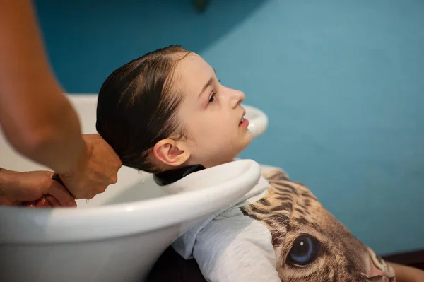 Στυλίστας κομμωτής κάνει ένα χτένισμα για ένα χαριτωμένο κοριτσάκι σε ένα σαλόνι ομορφιάς. Κομμωτήρια, κοπή μαλλιών. — Φωτογραφία Αρχείου