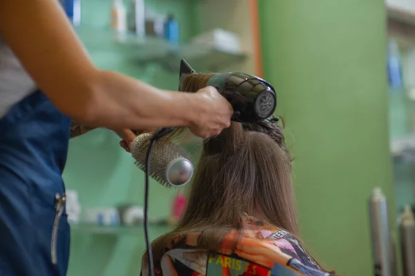 Stylist fodrász teszi a frizurát egy aranyos kislány egy szépségszalonban. Fodrászati, hajvágás. — Stock Fotó