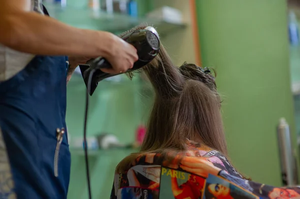 Stylist fodrász teszi a frizurát egy aranyos kislány egy szépségszalonban. Fodrászati, hajvágás. — Stock Fotó