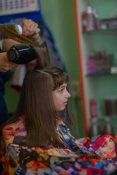 造型师理发师在美容院为一个可爱的小女孩做发型。理发、理发. — 图库照片
