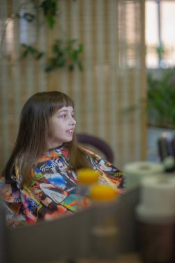 Stilist kuaför bir güzellik salonunda sevimli bir küçük kız için bir saç modeli yapar. Kuaförlük, saç kesimi.