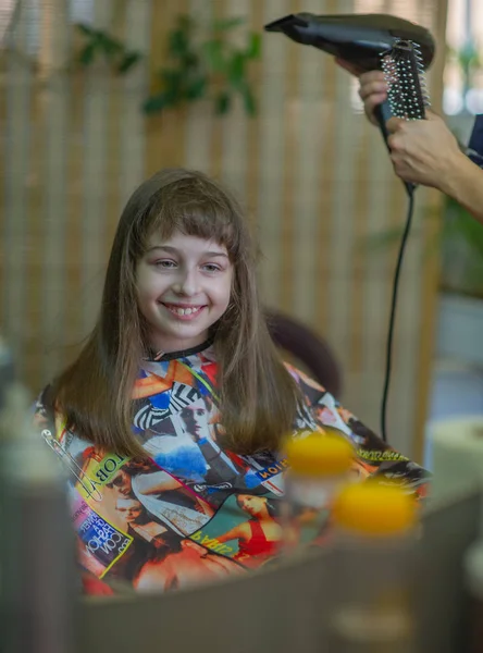 Stylist hairdresser makes a hairstyle for a cute little girl in a beauty salon. Hairdressing, hair cutting. — Stock Photo, Image