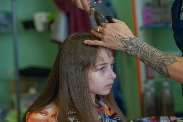 Cabeleireiro estilista faz um penteado para uma menina bonito em um salão de beleza. Cabeleireiro, corte de cabelo . — Fotografia de Stock