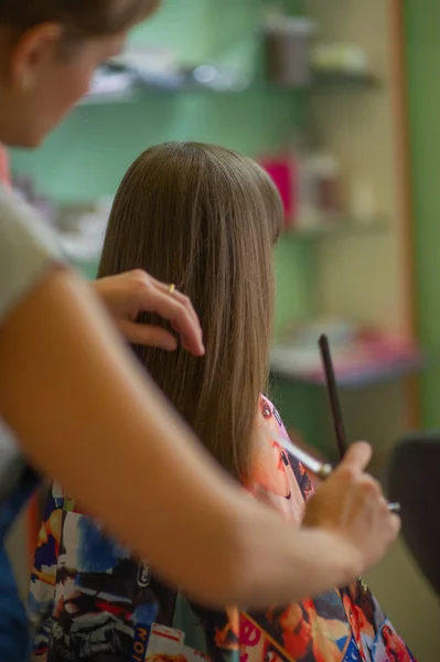 Stylist hairdresser makes a hairstyle for a cute little girl in a beauty salon. Hairdressing, hair cutting. — Stock Photo, Image