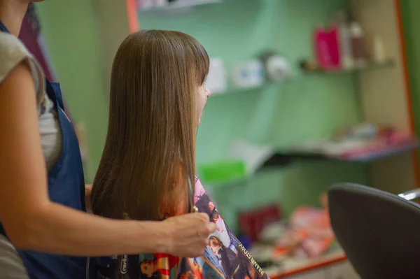 Stylist Friseur macht eine Frisur für ein nettes kleines Mädchen in einem Schönheitssalon. Friseur, Haarschnitt. — Stockfoto