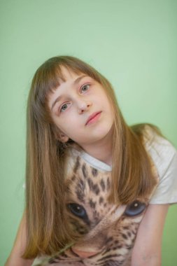 Kız 9 yaşında, yeşil bir arka planda. Kuaförlük, saç kesimi.