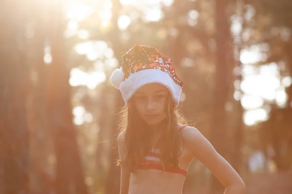 Ett barn leker med en jultomte hatt. Lycklig liten flicka i jultomten hatt utomhus på sommaren . — Stockfoto