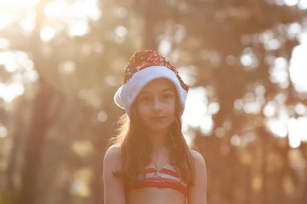 Un niño está jugando con un sombrero de Santa Claus. Feliz niña en Santa Claus sombrero al aire libre en verano  . — Foto de Stock