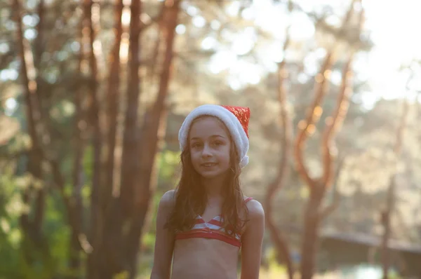 Un niño está jugando con un sombrero de Santa Claus. Feliz niña en Santa Claus sombrero al aire libre en verano  . —  Fotos de Stock