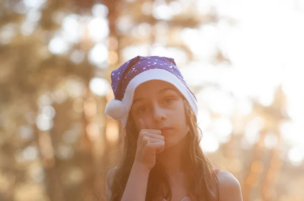 Dítě si zahrává s kloboukem na Santa Clause. Šťastná holčička v Santu v Santa Clause venku v létě . — Stock fotografie
