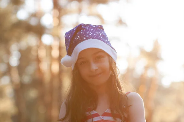 Un niño está jugando con un sombrero de Santa Claus. Feliz niña en Santa Claus sombrero al aire libre en verano  . —  Fotos de Stock
