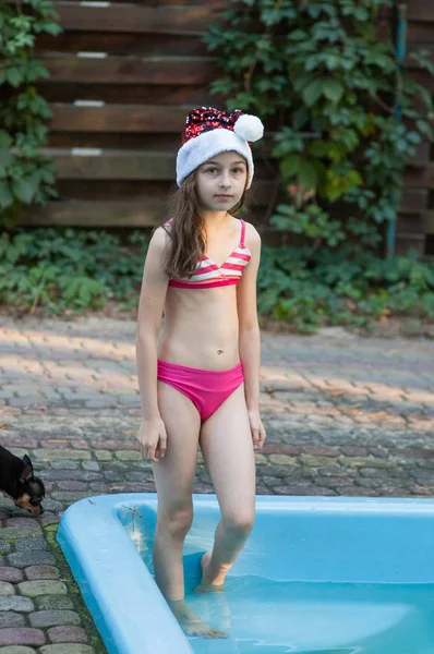 Fetiță într-o pălărie de Moș Crăciun lângă piscină — Fotografie, imagine de stoc