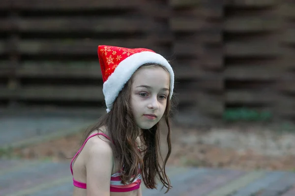 Menina em um chapéu de Papai Noel junto à piscina — Fotografia de Stock
