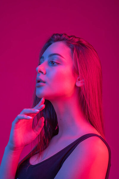 Крупный план лица красивой брюнетки в неоновом светло-красном и синем
.