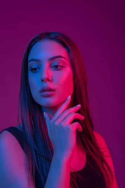Closeup rosto da bela mulher morena em néon luz vermelha e azul . — Fotografia de Stock