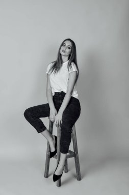 Esmer kız yüksek bar taburesinde oturuyor. Siyah beyaz fotoğraf