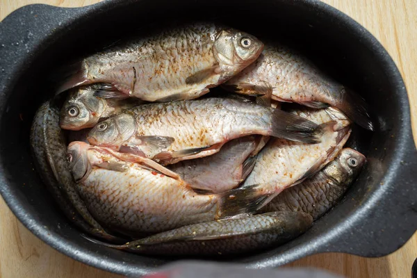 one crucian carp river fish in a round aluminum bowl on a wooden table