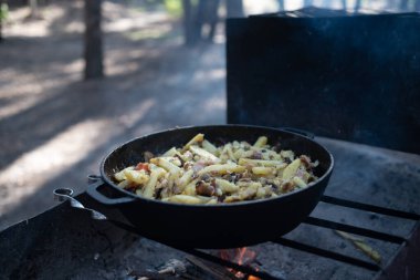 Ormanda ateşte kızartılmış patates dolu büyük bir tava.
