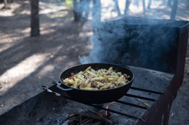 Ormanda ateşte kızartılmış patates dolu büyük bir tava.