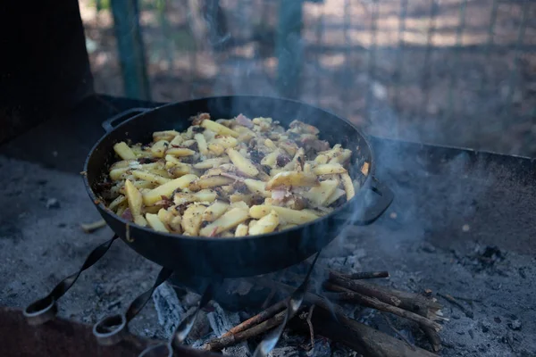 Hot big wok pan full of fried tasty potato on the fire in the forest — Stock Photo, Image