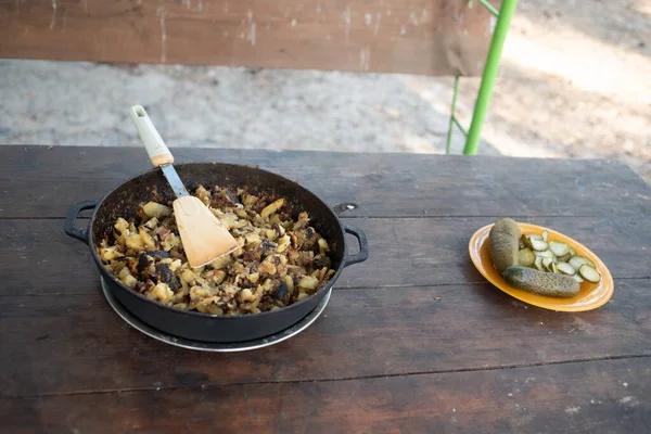 Hot big wok pan full of fried tasty potato on the fire in the forest