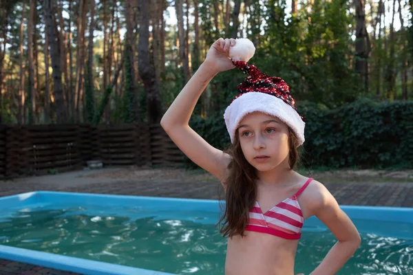 Un niño está jugando con un sombrero de Santa Claus. Feliz niña en Santa Claus sombrero al aire libre en verano . —  Fotos de Stock